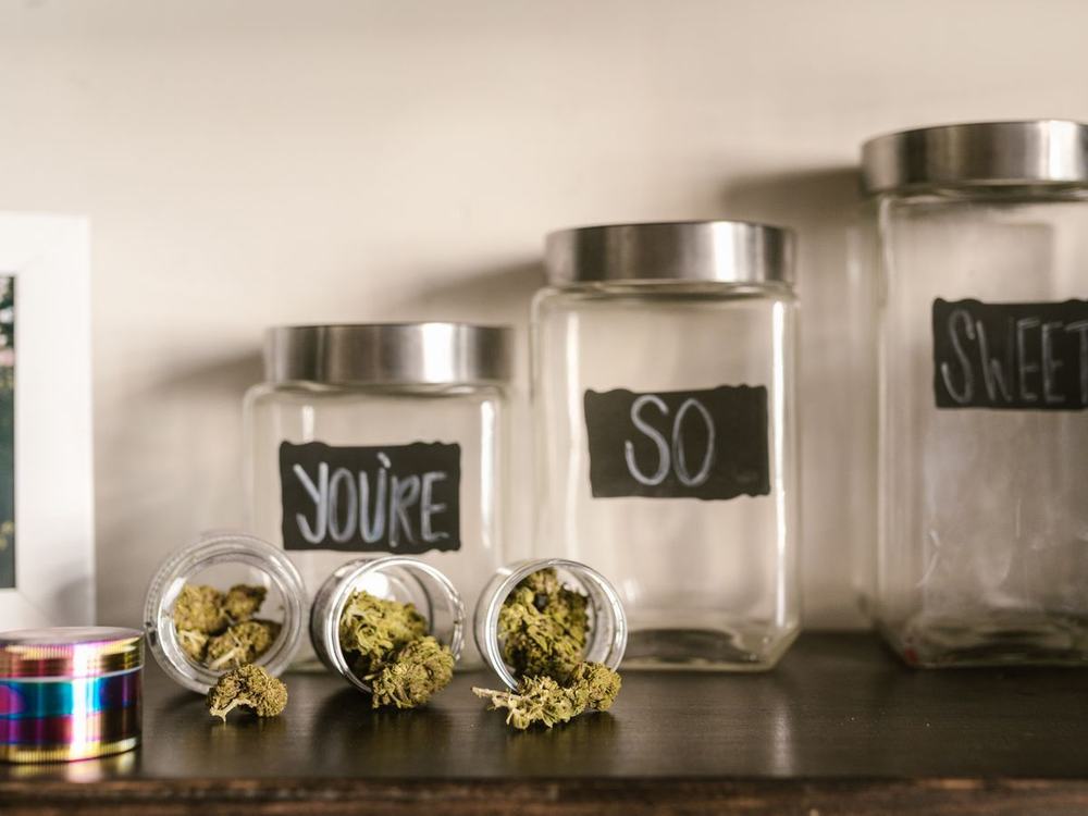 Labeled glass jars of cannabis flower lined up on a shelf
