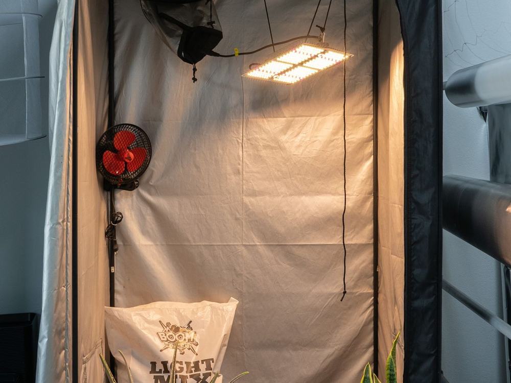 Indoor grow tent with an LED light, oscillating fan and a bag of soil